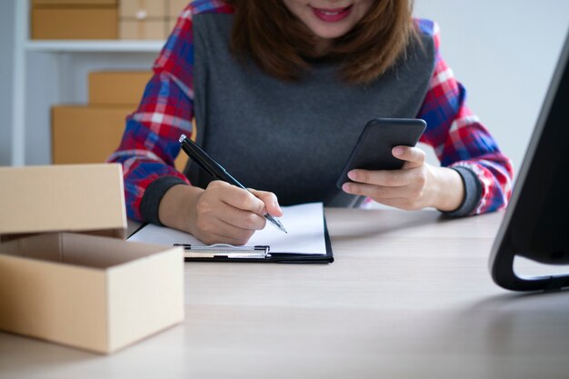 사진 소기업 소유자는 고객에게 패키지를 제공하기 위해 이름을 쓰고 있습니다. 중소 기업은 온라인 판매 및 온라인 제품 주문