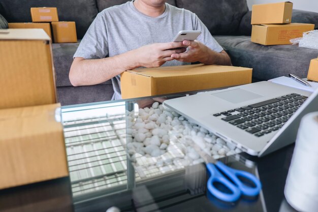 Small business parcel for shipment to client at home Young entrepreneur SME freelance man working online business by using smart phone with making on purchase order and preparing package product