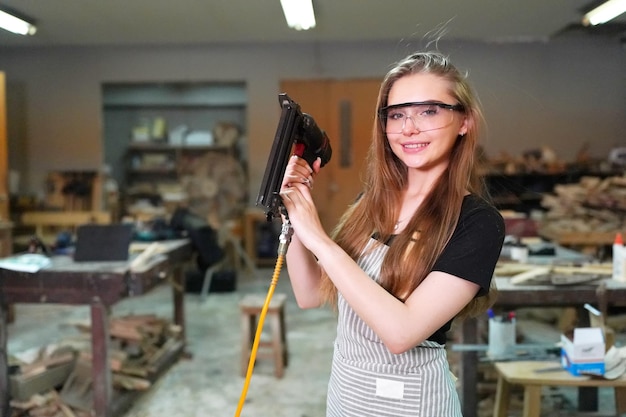 Small business of a young woman Beautiful young woman worker in a furniture workroom measuring wood