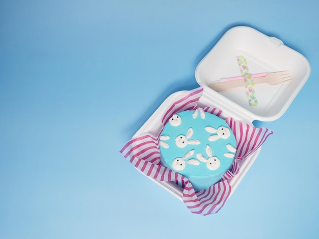포크와 양초가 있는 종이 상자에 담긴 작은 케이크 2인의 공간 복사