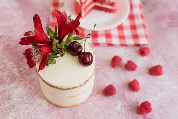 Foto una piccola torta bianca e rosa decorata con fiori e bacche