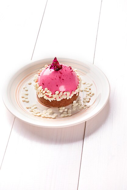 Small cake with different stuffing on a white plate. White wooden table. Still life. Copy space