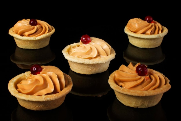 Small cakes with cream on a black background