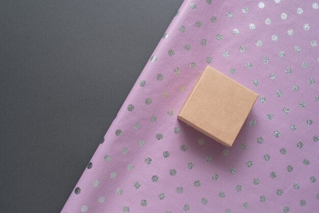 Small cardboard box and lilac polka dot wrapping paper, Gray table, Preparation for the holiday