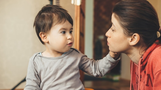 Small caucasian boy and his freckled mother discussing in the living room during the quarantine