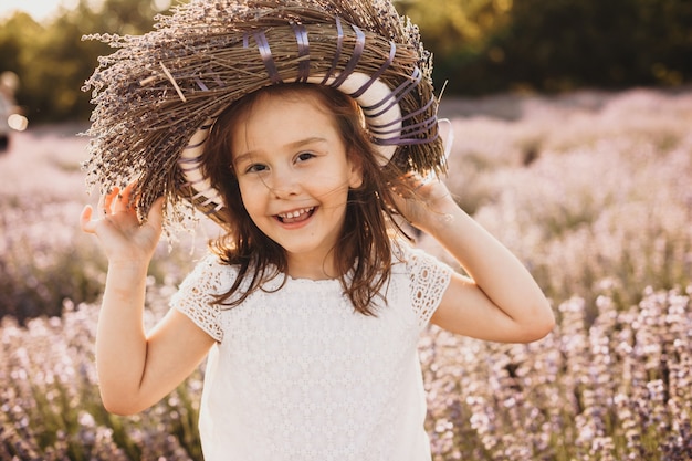 Small caucasian girl posing cheerfully in lavender field with a flower crown on head