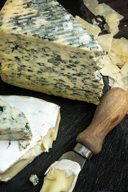 Фото Небольшой нож для сыра с кусочком вкусного бри рядом с большим тако из сыра с плесенью из молочной коровы