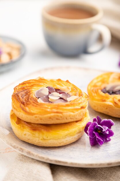Small cheesecakes with jam and almonds with cup of coffee on a white concrete
