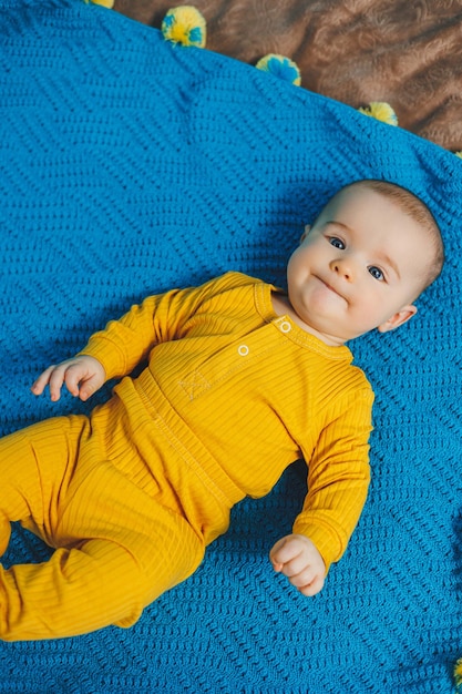 A small child 45 months old lies on a bed in yellow clothes The child begins to hold his head Baby clothes