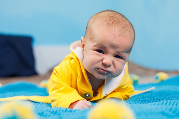 Маленький ребенок 45 месяцев лежит на кровати в желтой одежде Ребенок начинает держать голову Детская одежда