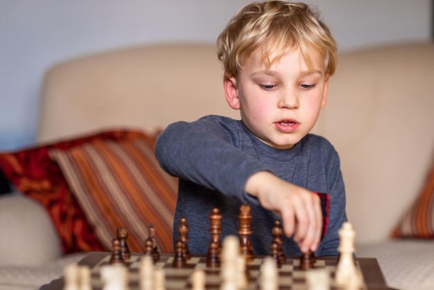 Young white child playing a game of chess on large chess board. Chess board  on table in front of school boy thinking of next move by Len44ik Vectors &  Illustrations with Unlimited