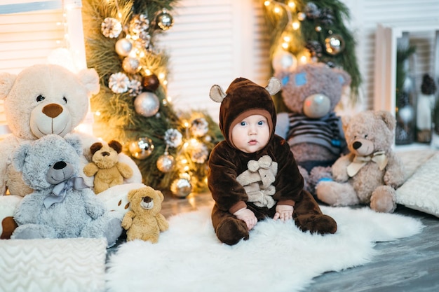 A small child in a brown teddy bear costume sits on the floor