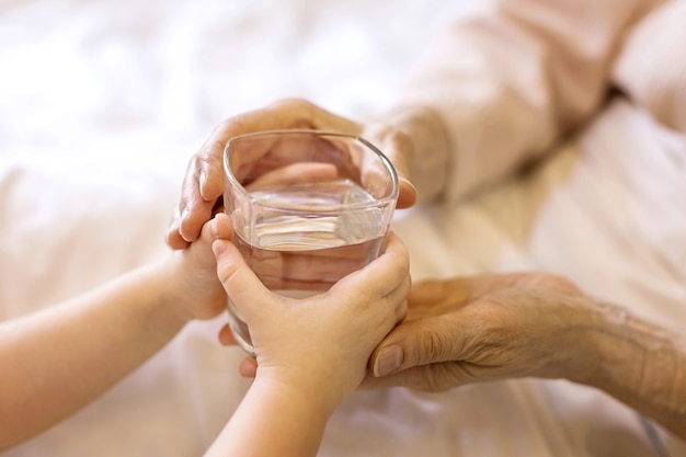 Un bambino piccolo dà un bicchiere d'acqua a una persona anziana