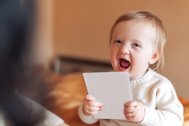 Photo small child at home smiling holds a white card