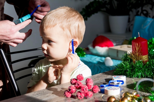 작은 아이가 귀에 토끼 모양의 크리스마스 트리 장난감을 걸었다