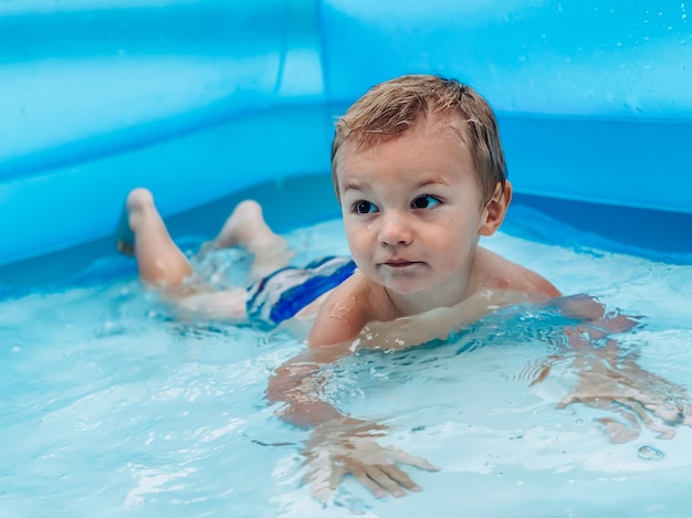 Un bambino piccolo in una piscina rotonda gonfiabile per bambini in condizioni di sole estivo. estate e concetto di vacanza.