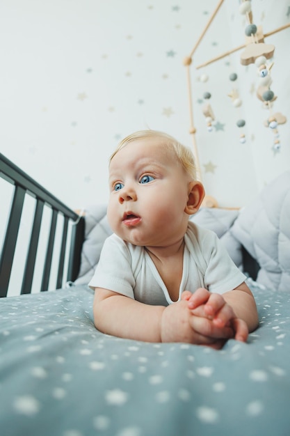 A small child is lying in a crib at home Portrait of a fivemonthold baby lying in a playpen Cheerful happy child