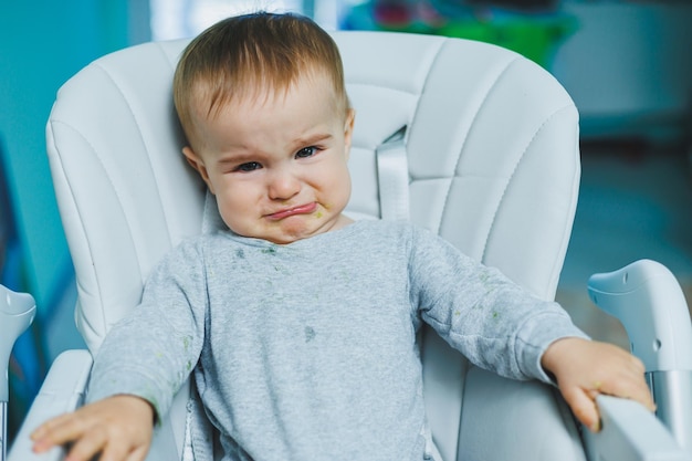 A small child is sitting on a high chair and crying baby chair\
for feeding a small child is sitting children\'s emotions