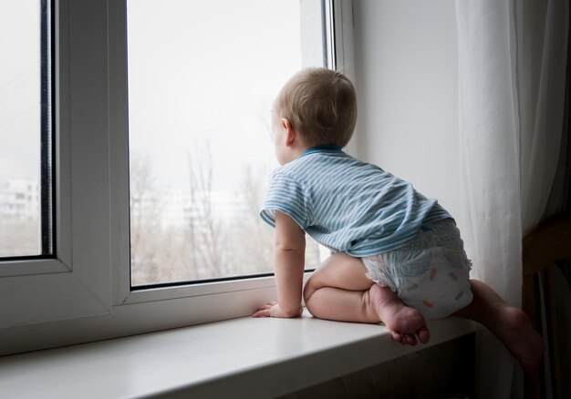 A small child is sitting on the window