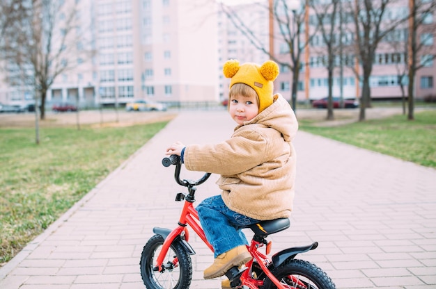 a small child learns to ride a bike for the first time in the city in spring