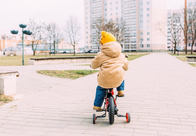 A small child learns to ride a bike for the first time in the city in spring