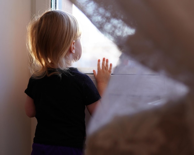 写真 窓の外を見ている小さな子供