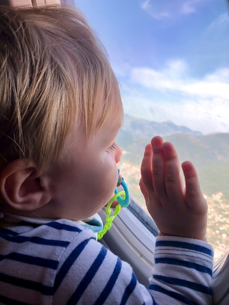 Un bambino piccolo guarda nel finestrino di un aeroplano. concetto di turismo.