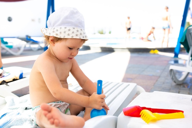파나마 모자를 쓴 작은 아이가 수영장 근처에서 화창한 날 여름에 놀고 있다
