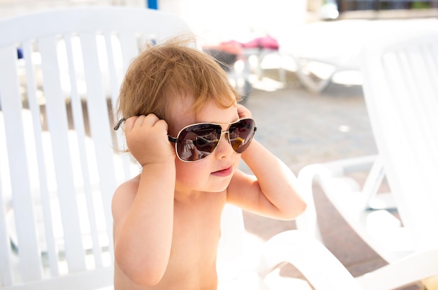 Small child in panama hat plays in the summer on sunny day near swimming pool