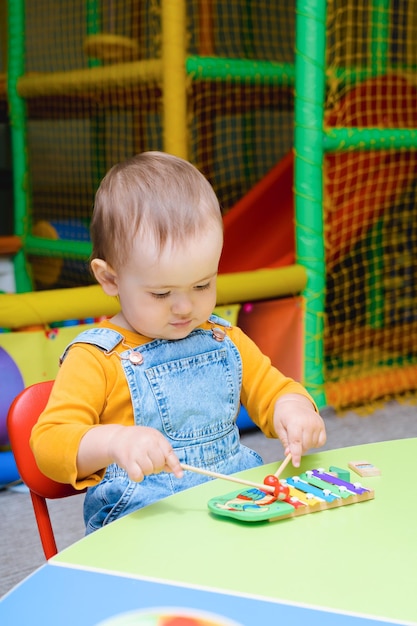 A small child plays with a xylophone in the playroom