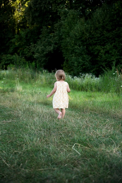 작은 아이가 공원의 길을 따라 달리고, 후면보기