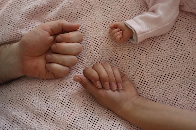 Рука маленького ребенка в взрослой мужской руке, открывающаяся в виде цвета Отец, мать и дочь