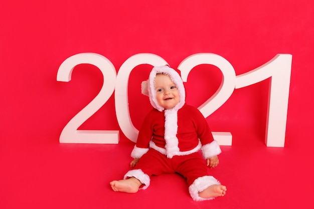 Маленький ребенок в костюме Санты сидит у новогодних номеров