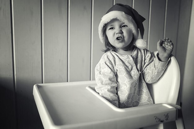 A small child in a santa hat monochrome