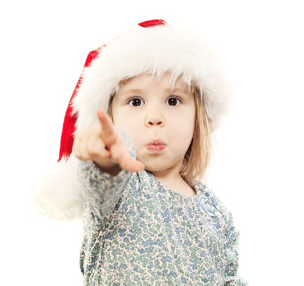 Small Child in Santa Hat Point her Finger on White. You bought me a gift? I want this thing!