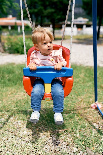 Small child sits on a swing and looks to the side