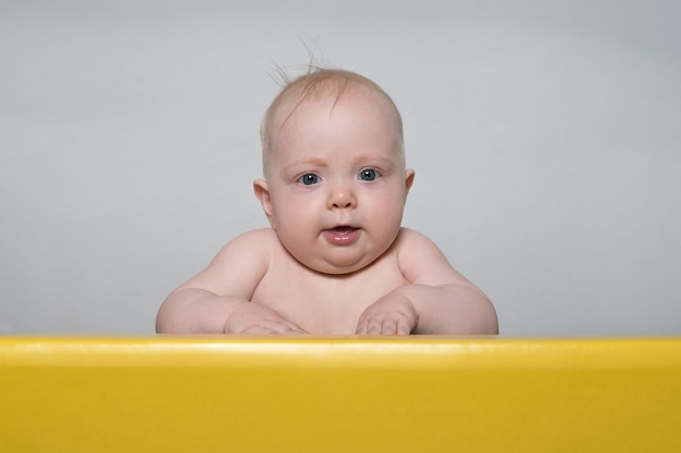 Small child sits at the table. Cute baby looking at camera and smiling.