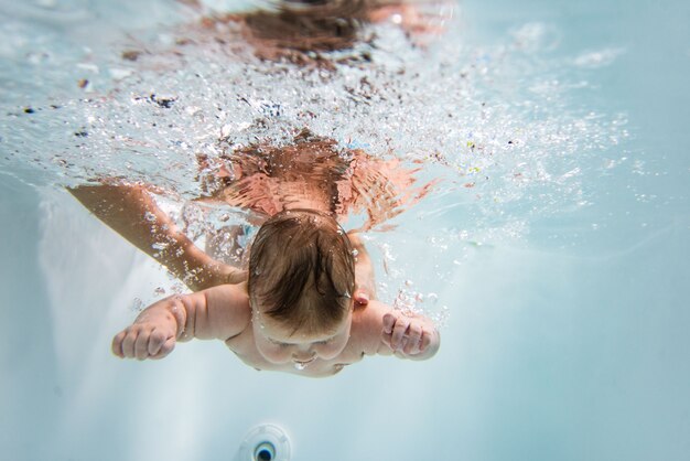 小さな子供が水中で泳ぎます。