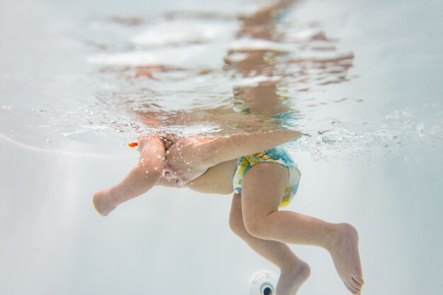 小さな子供が水中で泳ぎます。