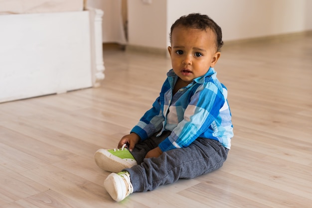 Small child tries to put on his shoes. Mixed race baby boy with shoes.