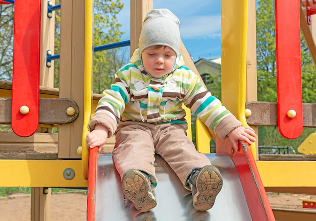 A small child wants to ride a wooden slide on the playground