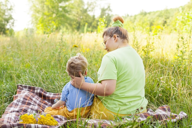 A small child in a wheelchair plays with his mother in the fresh air. Life in the educational age of disabled children,the concept of a happy disabled child.