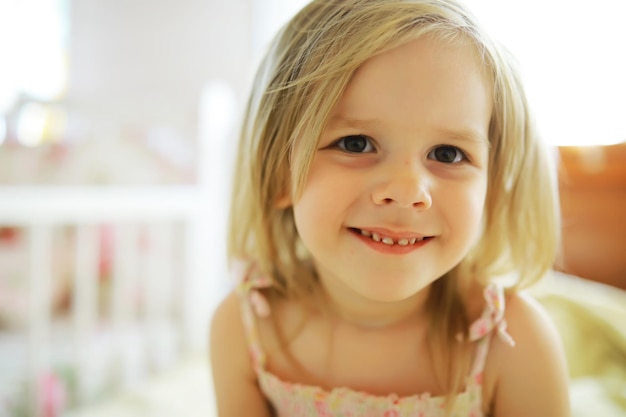 A small child with blond hair lies on the bed Baby girl is playing on the couch