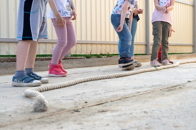 Small children boys and girls playing games jump over the rope getting ready to jump perspective on the legs