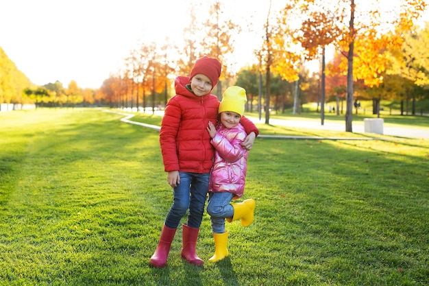 가을 공원에서 고무 장화와 밝은 옷을 입은 어린 아이들의 남매