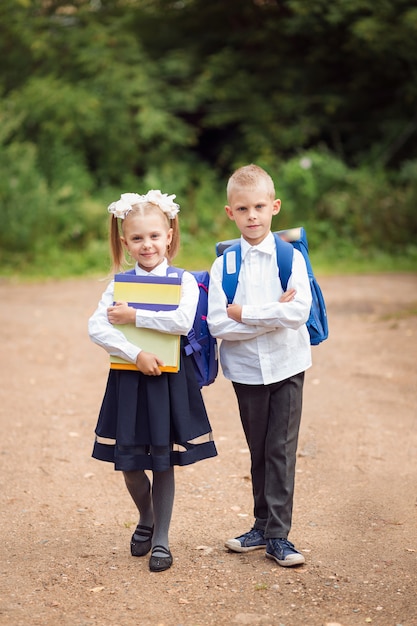 写真 小さな子供、1年生、学校の制服、バックパックと教科書、幸せな学生