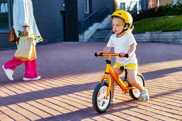 ヘルメットとバランスバイク屋外で遊ぶ小さな子供の女の子