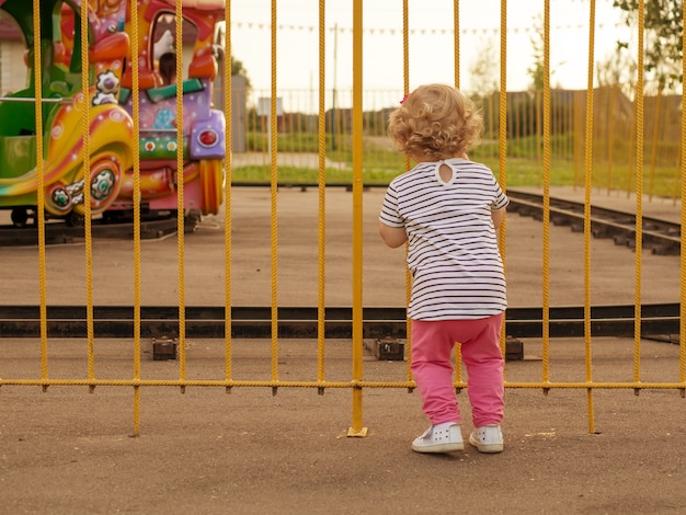 Small children look over the fence at the children's train and dream of a ride