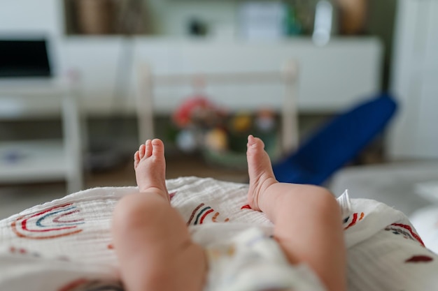 Small children's feet are lying on the bedspread. Cute newborn concept