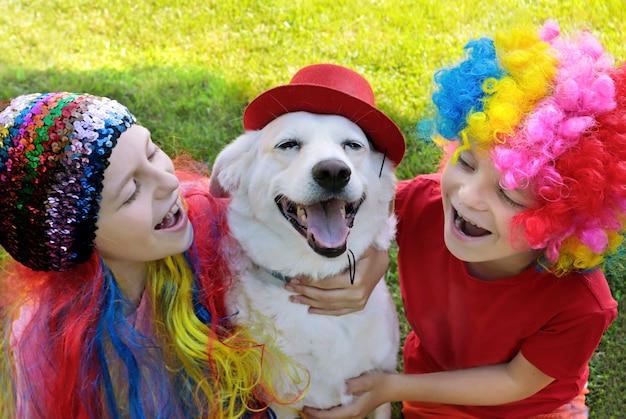 Small children in smart suits play with a dog in nature.